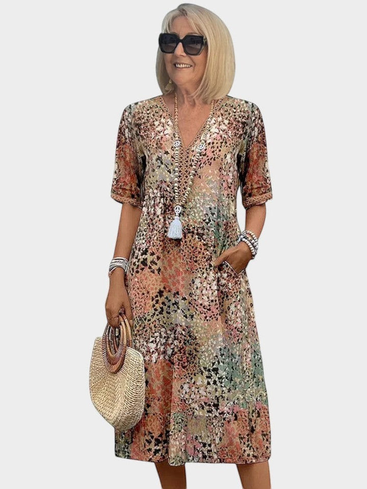Victoria Boutique midi dress in a vibrant abstract print with a V-neckline, lace trim, and side pockets.