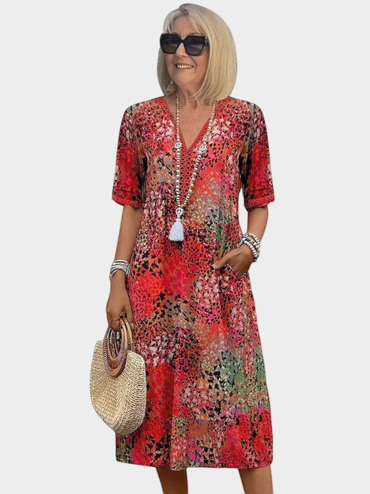 Victoria Boutique Lauren midi dress in fuchsia abstract print with V-neck, lace trim, and side pockets on a model.