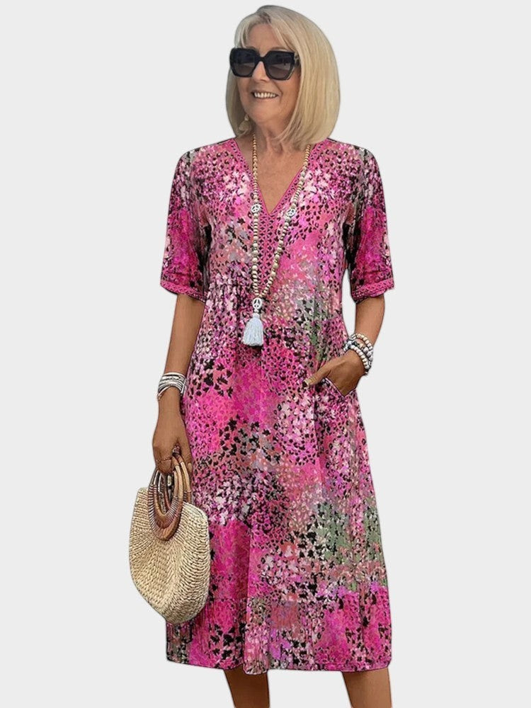 Victoria Boutique Lauren midi dress in fuchsia abstract print with V-neckline, lace trim, and side pockets.